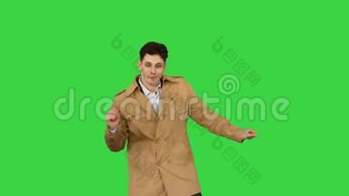 年轻人穿着<strong>风衣</strong>跳舞，在绿色屏幕上玩得很开心，ChromaKey。